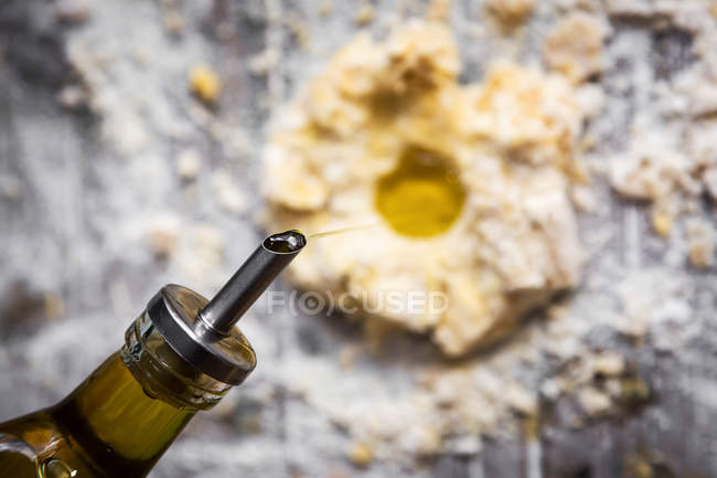 Above of bottle pouring oil in pile of flour on rural wooden table — Stock Photo