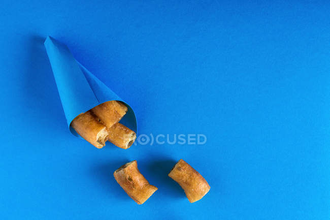 Churros in paper cone on blue — Stock Photo