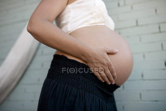 Unrecognizable pregnant holds her belly. Close up, profile view of tummy. — Stock Photo