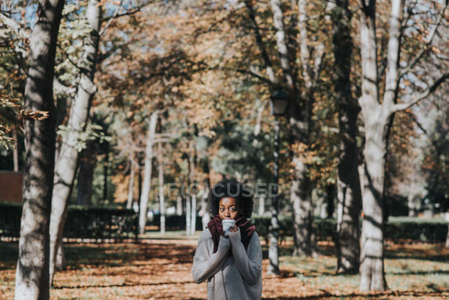 Portrait of girl drinking coffee at park alley on sunny day — Stock Photo