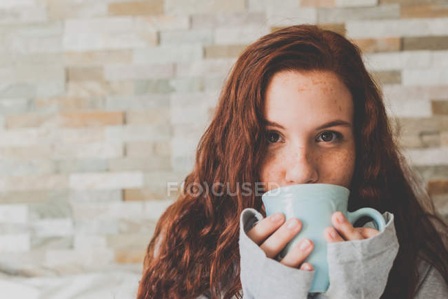 Mulher de gengibre bebendo café de copo azul — Fotografia de Stock