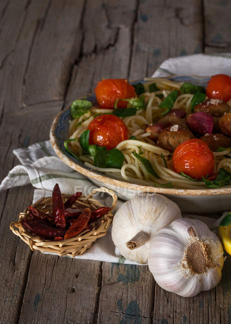 Espaguetis y albóndigas adornados con hojas de albahaca y tomates a la parrilla en bandeja - foto de stock