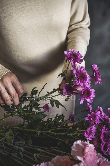 Середина жіночого флориста, який бере квітку з букету — стокове фото