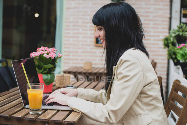Mulher usando laptop no terraço do café — Fotografia de Stock