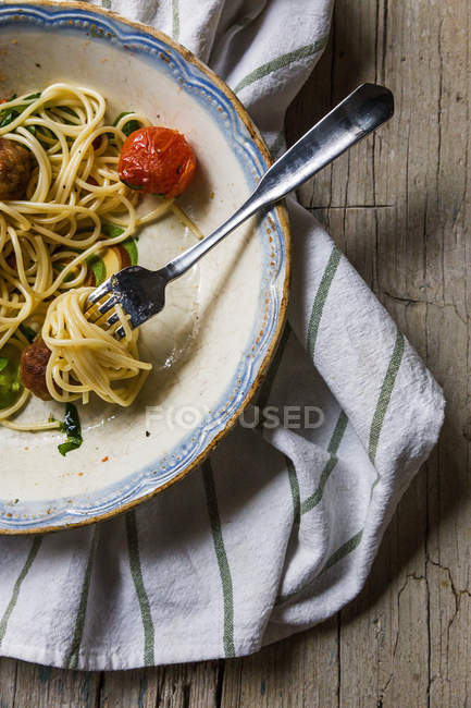 Обрезанный вид вилки с катушкой пасты на тарелке с обычными itlaian спагетти — стоковое фото