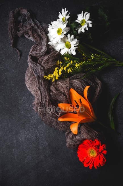 Padrão floral criativo com várias flores coloridas e tecido de olhar na superfície escura — Fotografia de Stock
