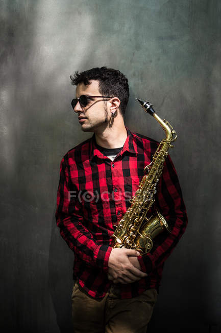 Saxophoniste debout avec instrument et regardant de côté — Photo de stock