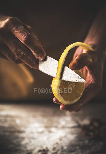 Close up view of hands cutting off lemon peel — Stock Photo