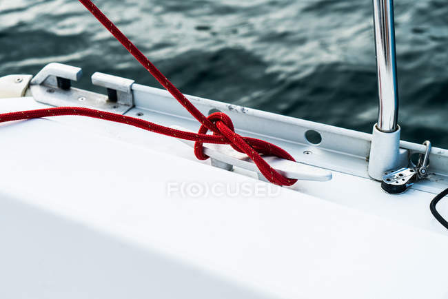 Vista de cerca del cable rojo envuelto alrededor de aparejo en la cubierta del yate - foto de stock