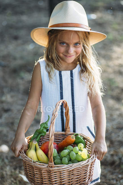 Enfant expressif posant avec panier de fruits — Photo de stock