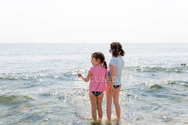 Hermanas jugando en la playa y cogidas de la mano . - foto de stock
