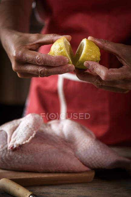 Primer plano de la mujer exprimiendo limón fresco en el pollo crudo - foto de stock
