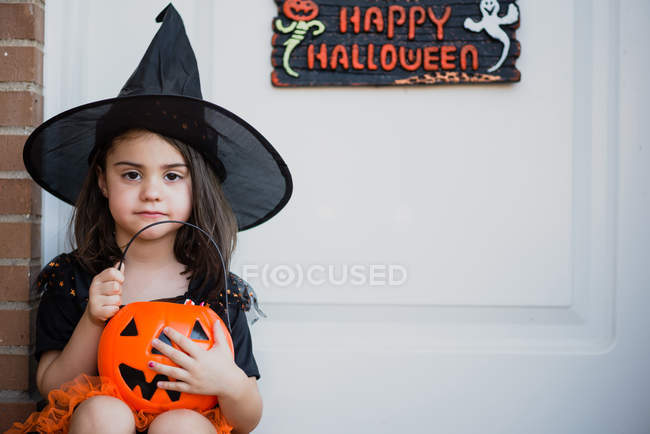 Menina em traje de bruxa sentado no alpendre — Fotografia de Stock