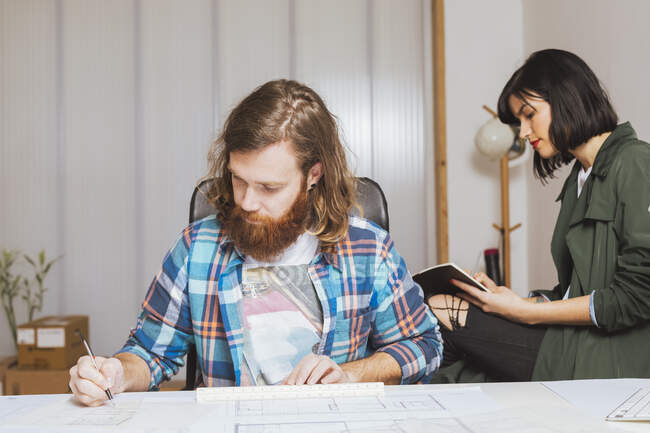 Ritratto frontale di uomo e donna seduti e al lavoro in ufficio — Foto stock