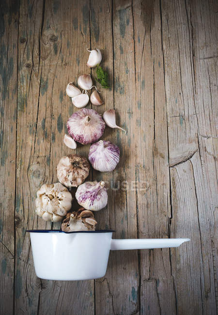 Arrangement of fresh garlic and metal scoop on wooden table — Stock Photo