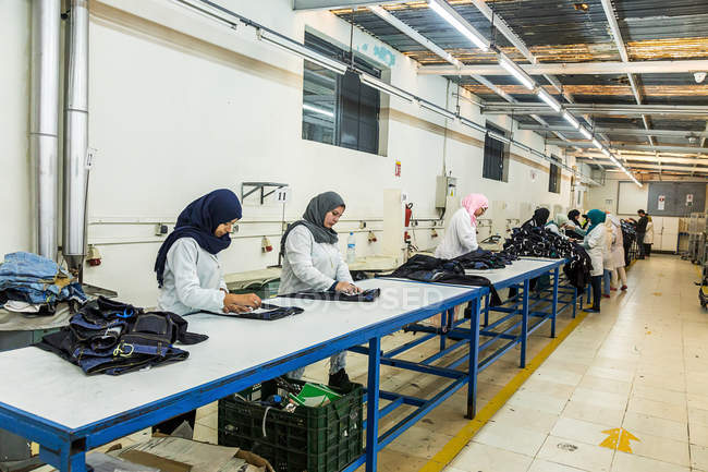 TANGIER, MARRUECO- 18 de abril de 2016: Los trabajadores que trabajan en línea en la confección fabrican - foto de stock