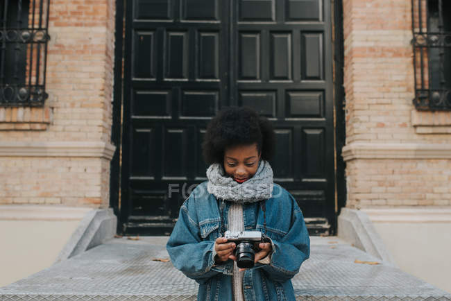 Portrait of girl wearing denim looking down at analog camera in hands — Stock Photo