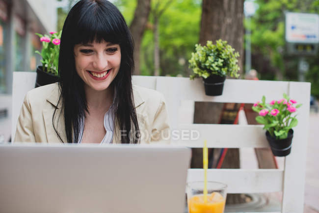 Жінка працює на ноутбуці за терасним столом — стокове фото