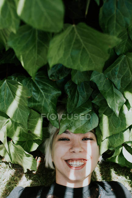 Girl lying on green leaves and looking at camera — Stock Photo