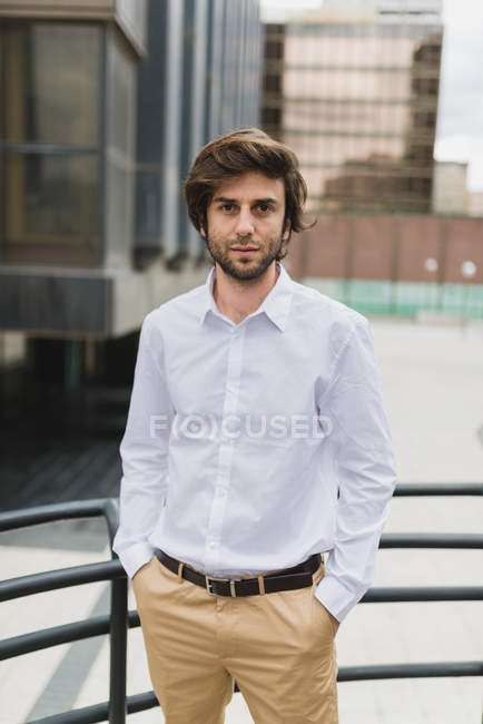 Portrait of confident businessman in white shirt posing at downtown urban scene and looking at camera — Stock Photo