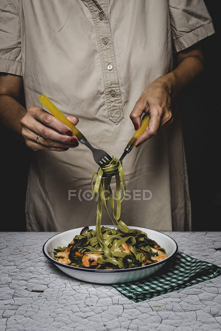 Midsection of woman winding on fork italian green tagliatelle — Stock Photo
