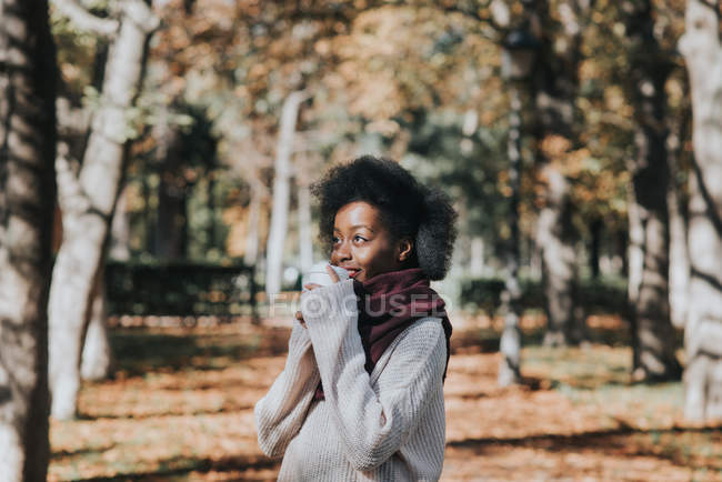 Портрет милой девушки, позирующей с чашкой кофе осенью в солнечный день — стоковое фото