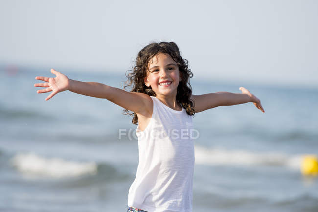 Retrato de chica sonriente alegre con los brazos ensanchados en la playa
. - foto de stock
