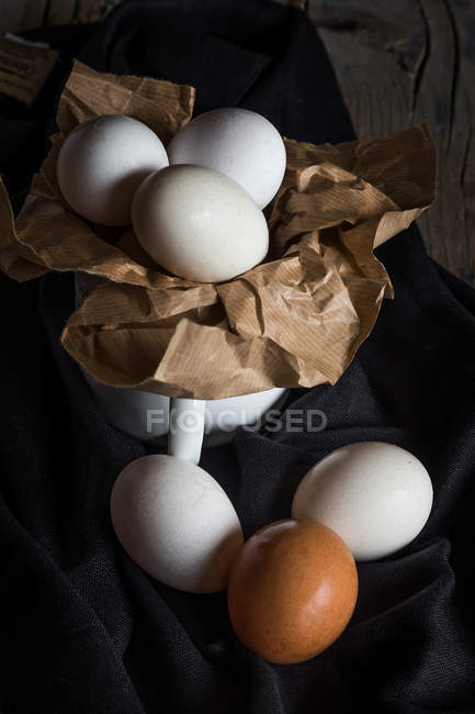 Bodegón de huevos de gallina en taza sobre tela rural - foto de stock