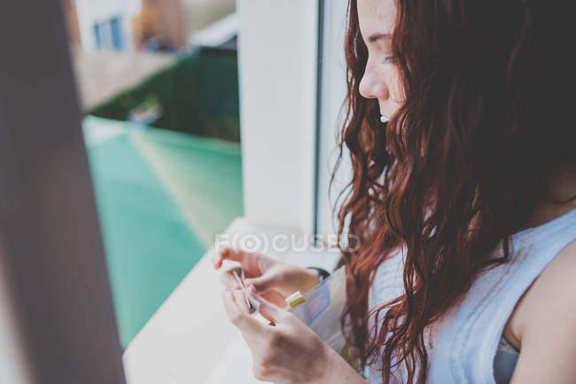 Mädchen rollt Zigarette neben Fenster — Stockfoto