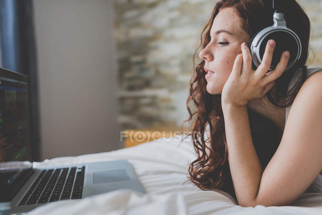 Mulher de gengibre ouvindo música e usando laptop — Fotografia de Stock