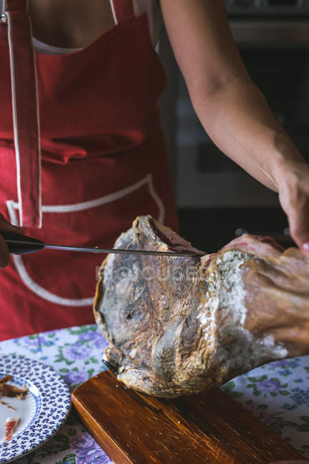 Mains féminines tranchant le jambon Serrano avec un couteau — Photo de stock