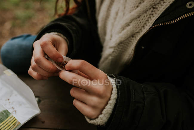 Imagen recortada de manos femeninas rodando cigarrillo - foto de stock