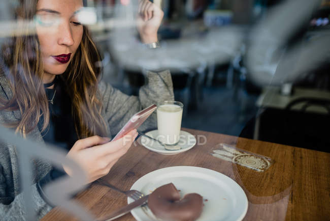 Girl using smartphone in beanery. — Stock Photo