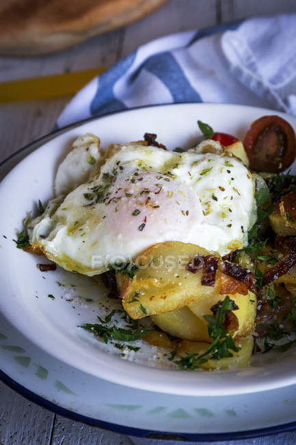 Пластины с жареным яйцом и картофелем в тарелке на сельском столе — стоковое фото