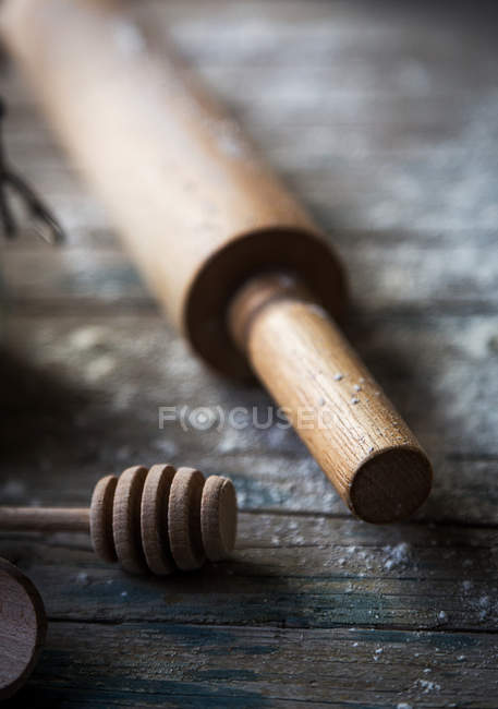 Vista de cerca de la cuchara de miel de madera y rodillo en la mesa rústica - foto de stock