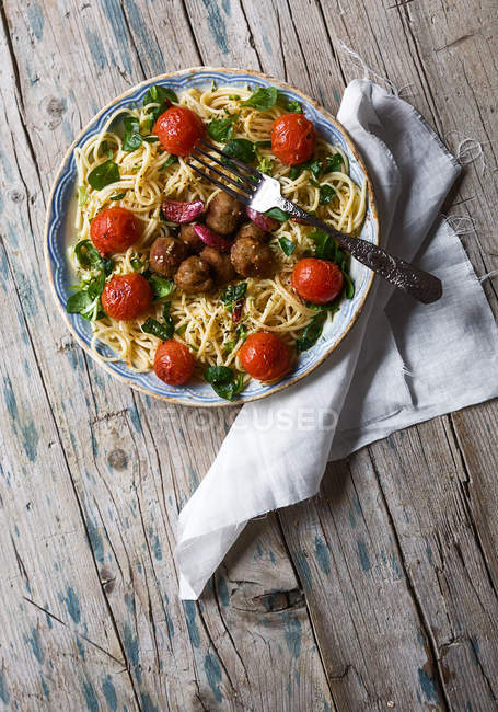Vista superior do garfo na placa de espaguete com almôndegas e tomates cereja na mesa rústica de madeira — Fotografia de Stock