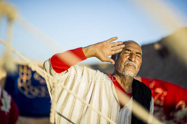 Porträt eines älteren arabischen Mannes, der in die Kamera blickt und eine Grußgeste zeigt. — Stockfoto
