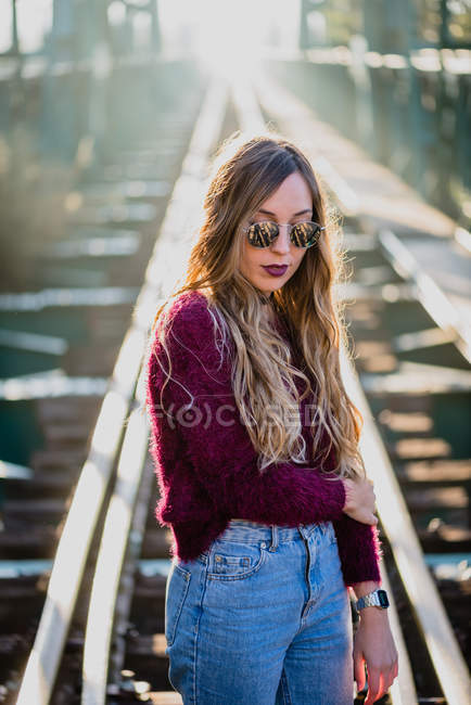 Ragazza in occhiali da sole in posa sul ponte ferroviario — Foto stock