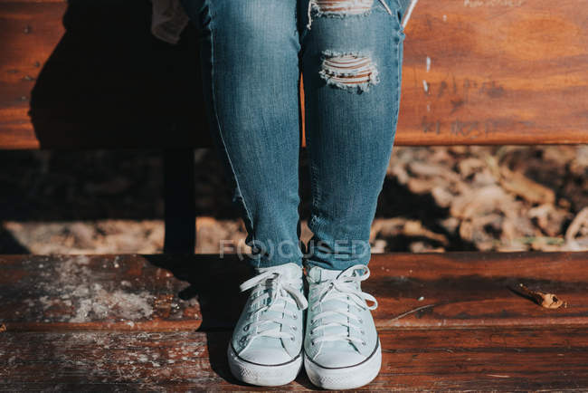 Tiefschnitt-Ansicht weiblicher Beine in Keds auf Parkbank — Stockfoto