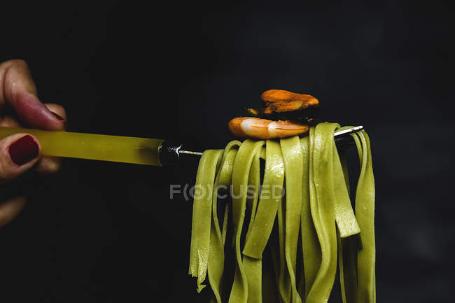 Green tagliatelle with seafood on fork on black background — Stock Photo