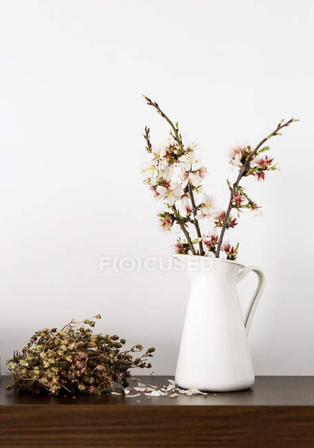 Fresh cut blooming sprigs in vase on shelf — Stock Photo
