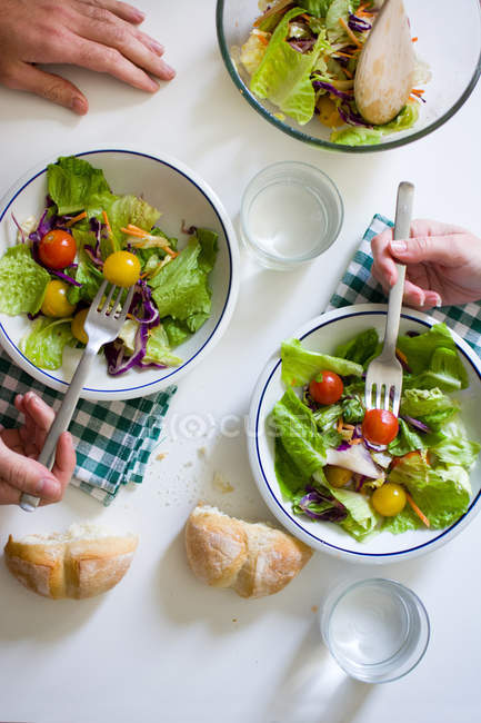 Von oben nehmen Hände Salat von den Tellern — Stockfoto