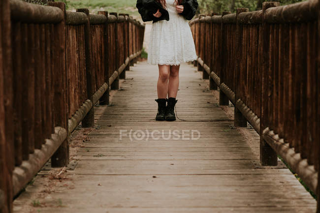 Section basse de fille en robe blanche sur pont en bois — Photo de stock
