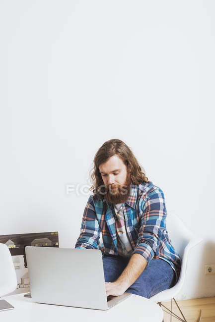 Varón barbudo trabajando en el ordenador portátil - foto de stock