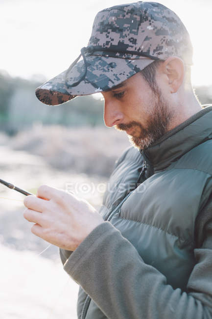 Retrato del hombre maduro preparando anzuelo para pescar en el río - foto de stock