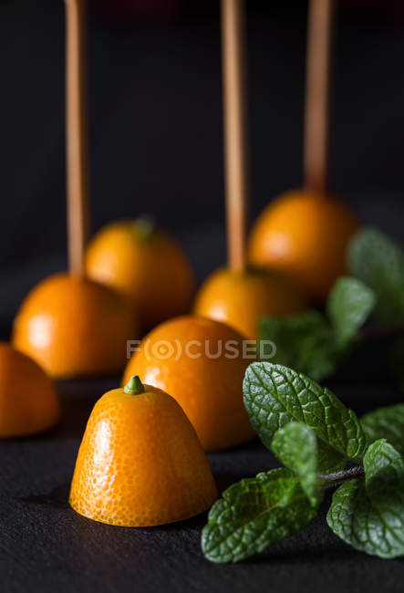 Primo piano di kumquat freschi dimezzati su bastoncini con zecca — Foto stock