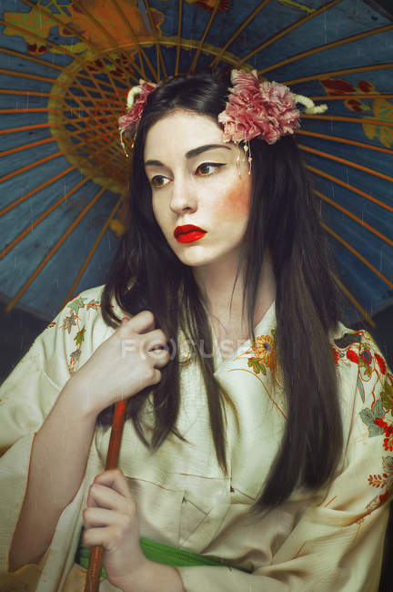 Mujer joven con maquillaje asiático sosteniendo paraguas azul asiático . - foto de stock
