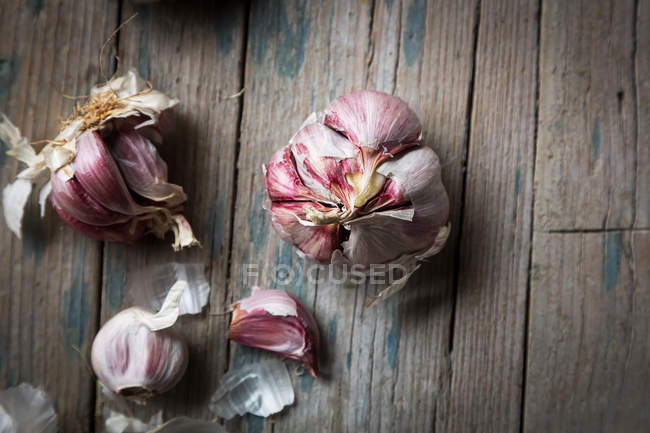 Fresh garlic bulbs and cloves on wooden surface — Stock Photo