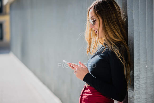 Девушка в солнечных очках с помощью смартфона — стоковое фото