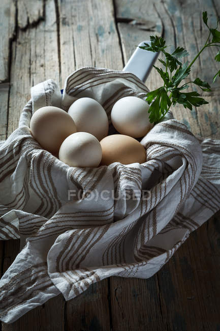 Натюрморт из куриных яиц полотенце и совок на сельском столе — стоковое фото